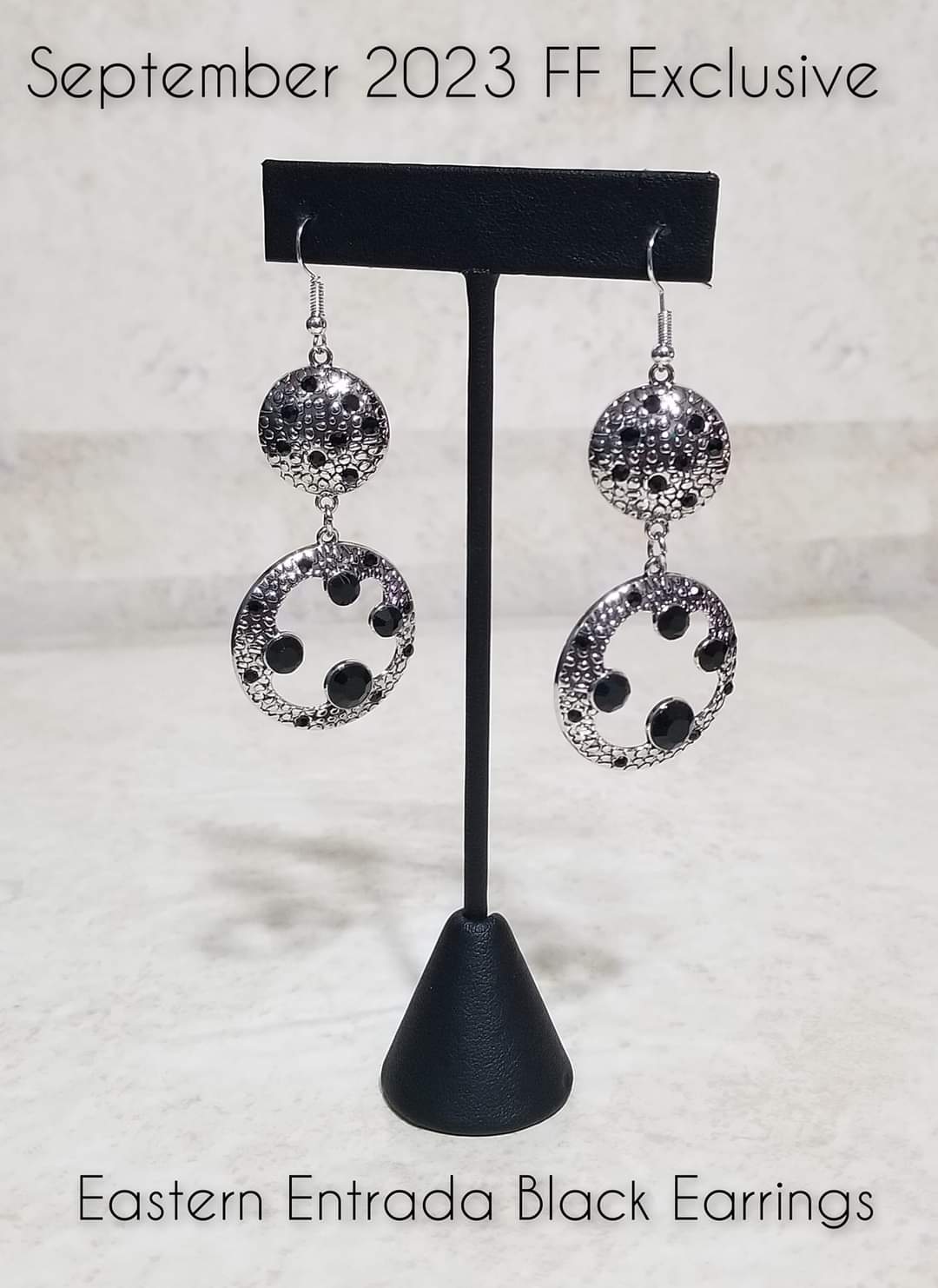 Eastern Entrada - Black and Silver Earrings - Paparazzi Accessories - Dotted with dainty black rhinestones and embossed in pebble-like textures, a beveled silver circle attaches to an imperfect silver hoop featuring matching texture. A smattering of oversized black rhinestones haphazardly adorns the hoop, resulting in a gritty shimmer.