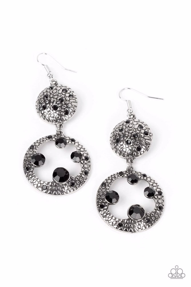 Eastern Entrada - Black and Silver Earrings - Paparazzi Accessories - Dotted with dainty black rhinestones and embossed in pebble-like textures, a beveled silver circle attaches to an imperfect silver hoop featuring matching texture. A smattering of oversized black rhinestones haphazardly adorns the hoop, resulting in a gritty shimmer.