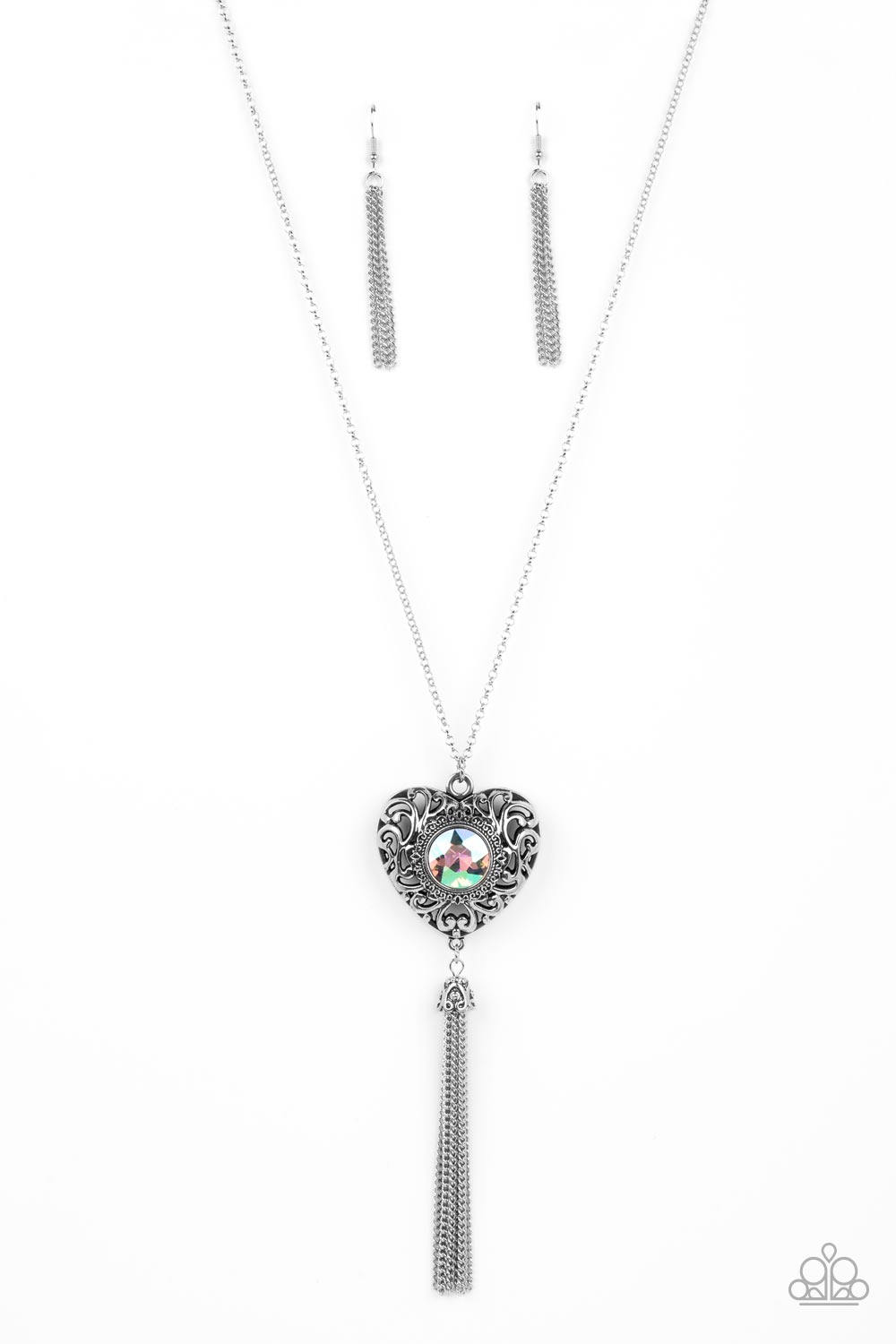 Prismatic Passion - Green Iridescent and Silver Necklace - Paparazzi Accessories - A magical iridescent green gem sparkles at the center of a 3-dimensional silver heart. Filled with vine-like filigree, the locket-inspired heart pendant glides along an extended silver chain while a shimmery tassel of silver chain dances from the bottom for a flirtatious finish. Features an adjustable clasp closure.